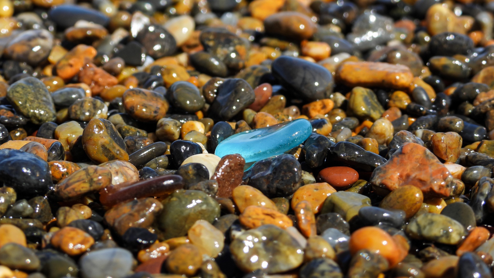 Гладкие разноцветные мелкие камни на пляже 