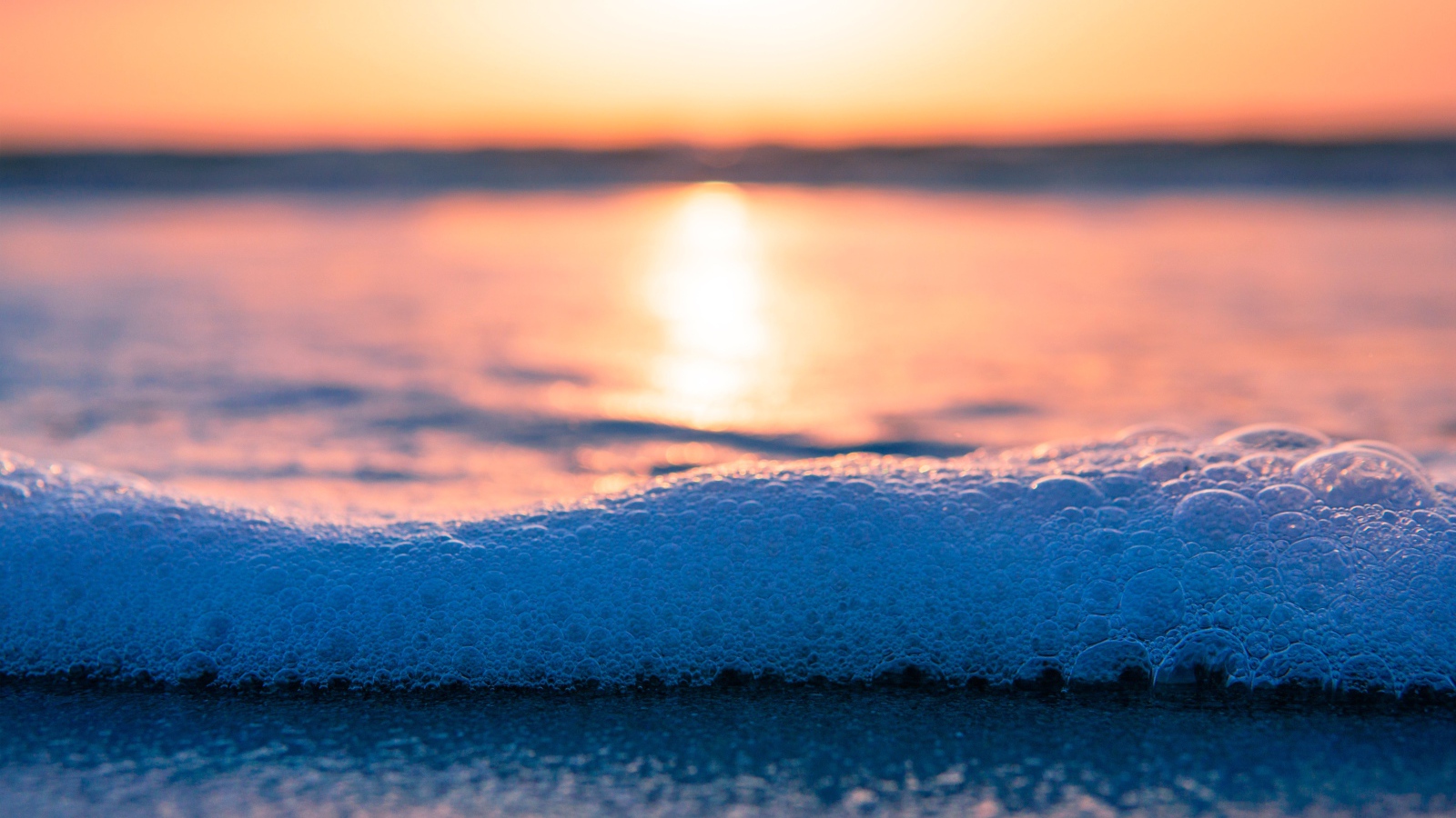 Белая морская пена с пузырям на закате