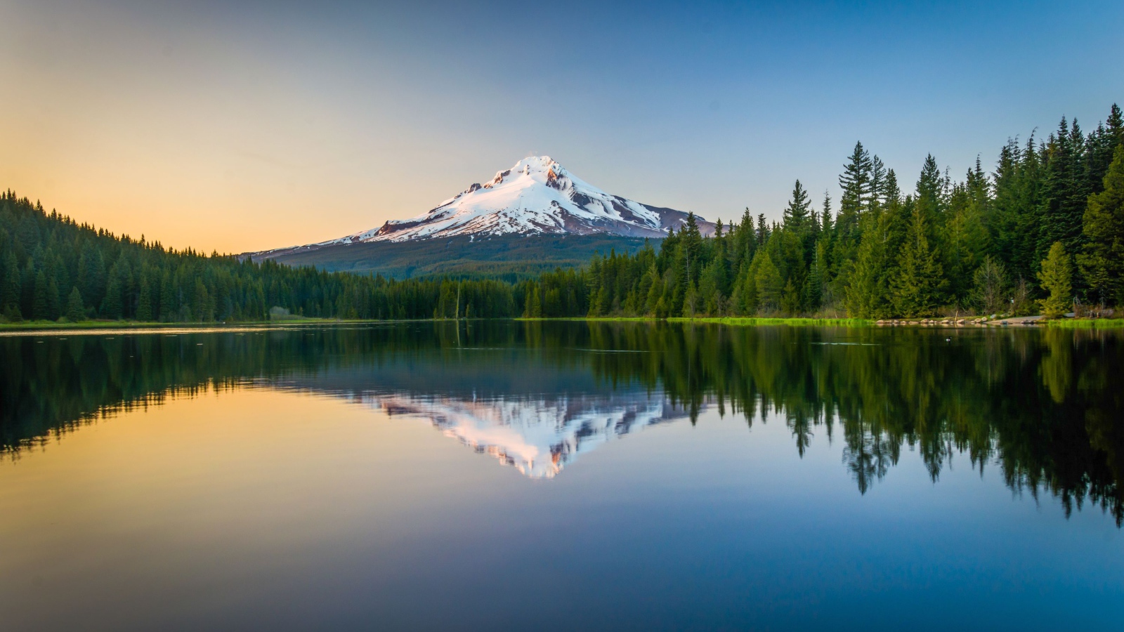 Заснеженная вершина вулкана отражается в холодной воде озера 