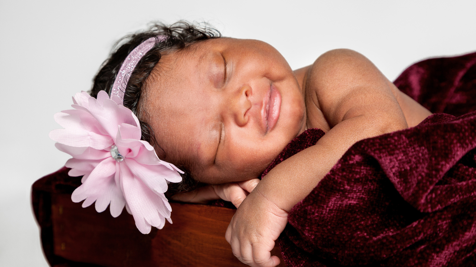 Темнокожая маленькая девочка с розовым цветком на голове 