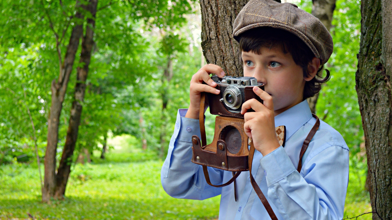 Мальчик с фотоаппаратом в руках в парке