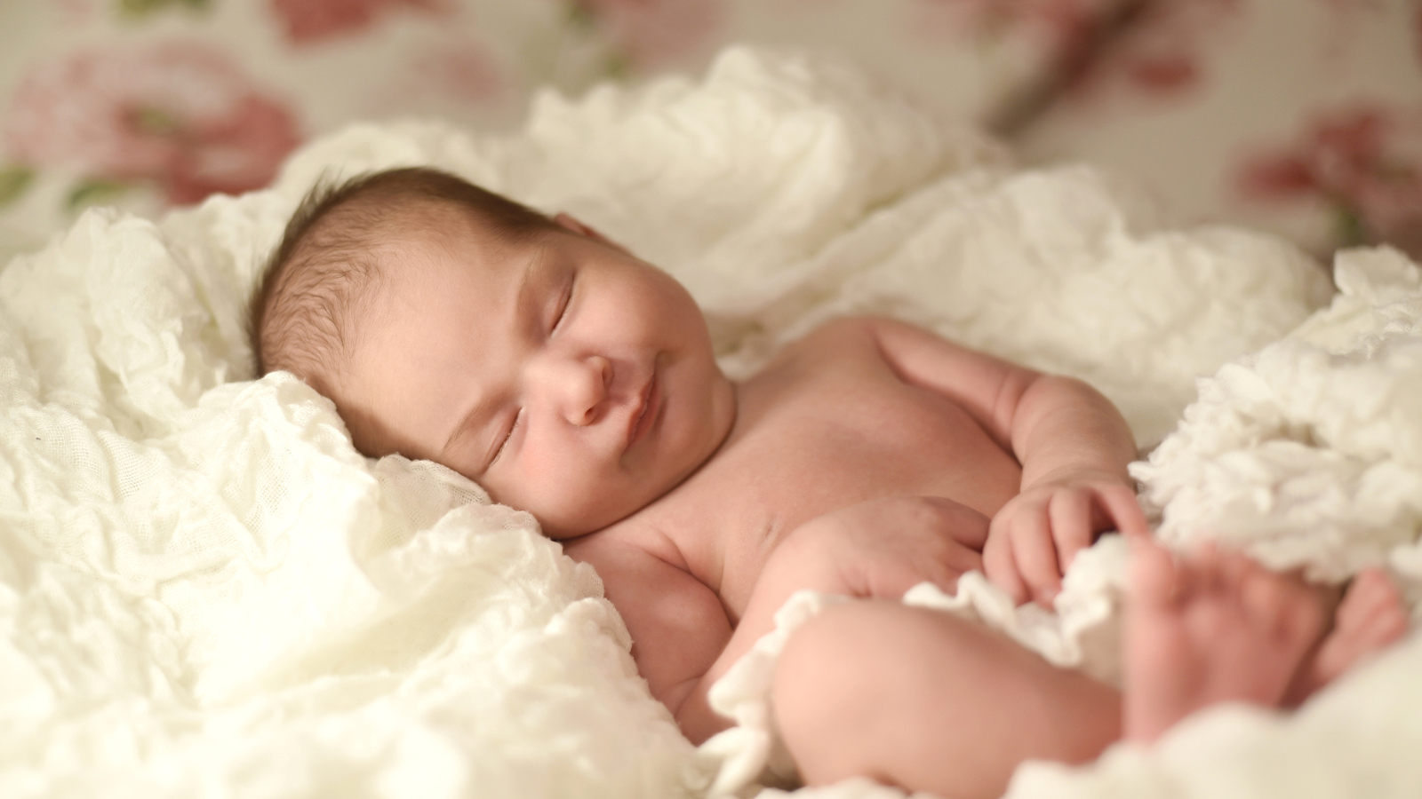 Милый грудной ребенок спит на белом покрывале 