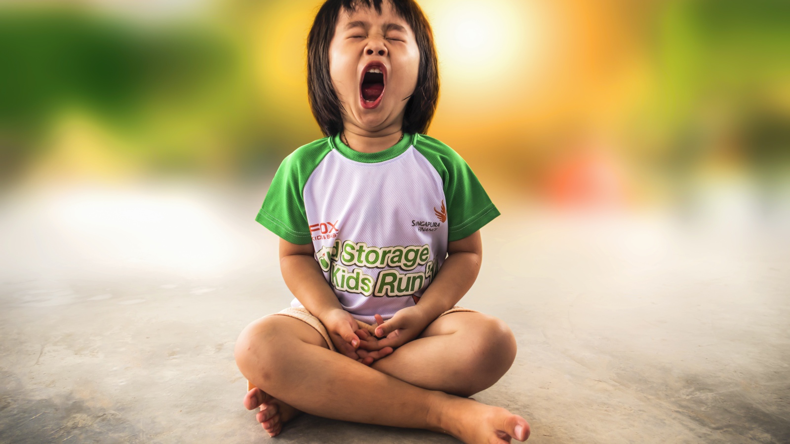 Маленькая девочка азиатка зевает на полу