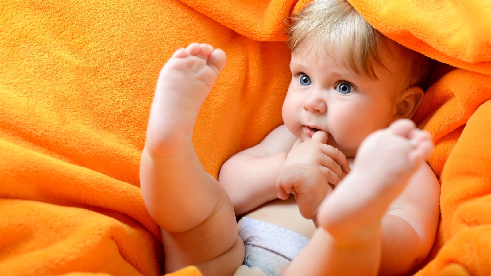 Маленький голубоглазый ребенок в желтом покрывале 