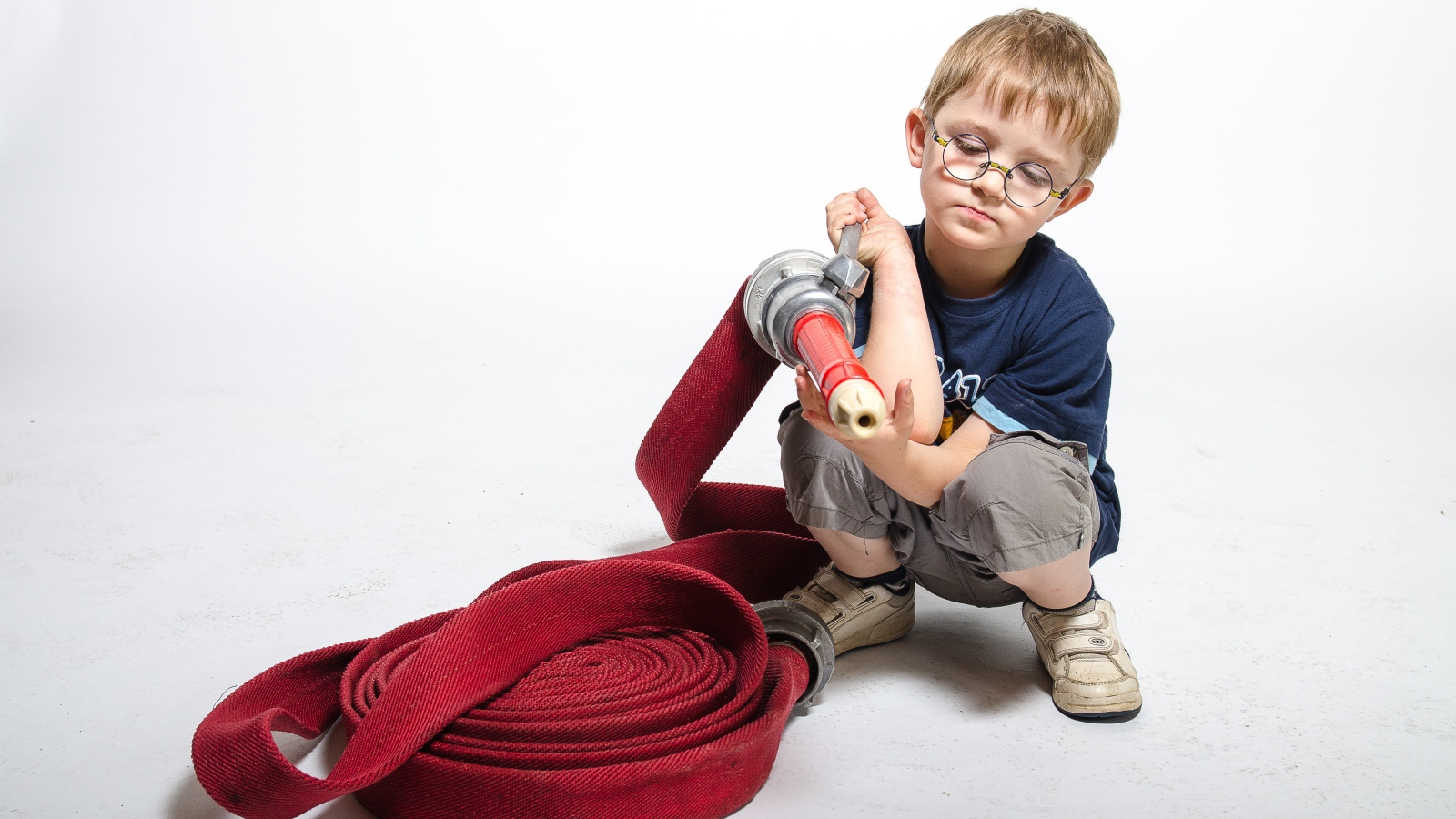Маленький мальчик на белом фоне играет в пожарного