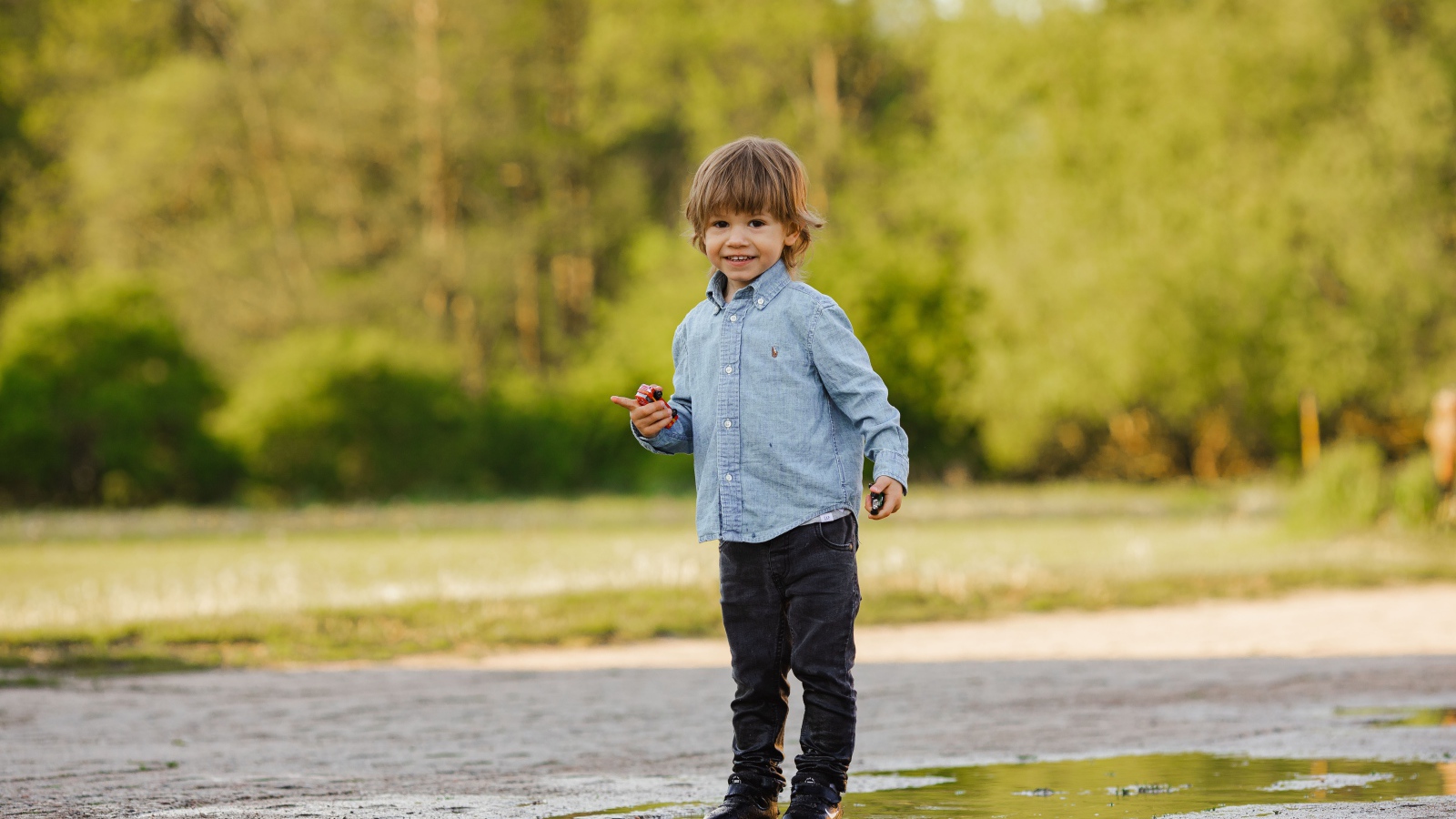 Маленький мальчик стоит в луже на дороге 