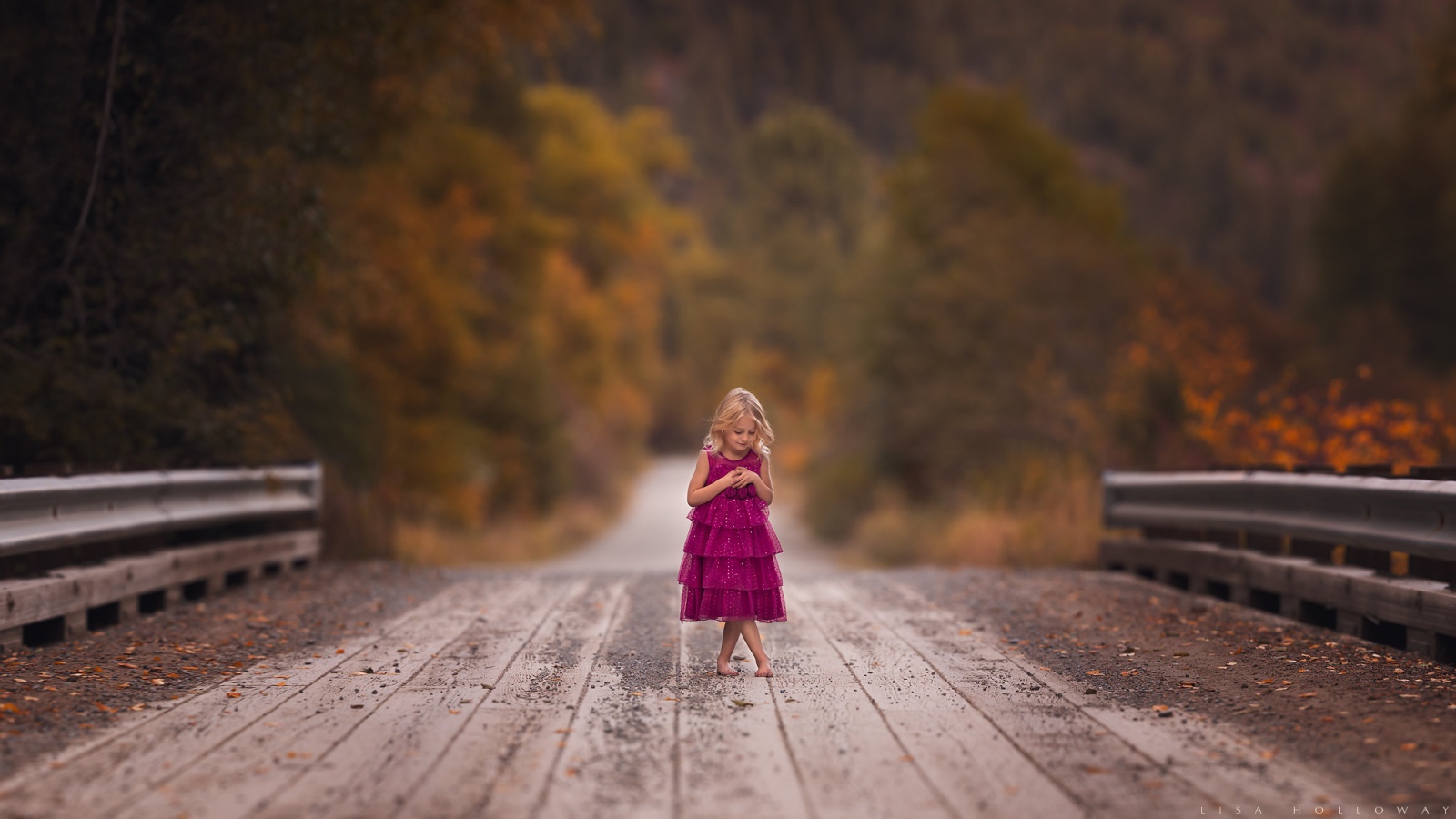 Little girl in a dress stands on the bridge
