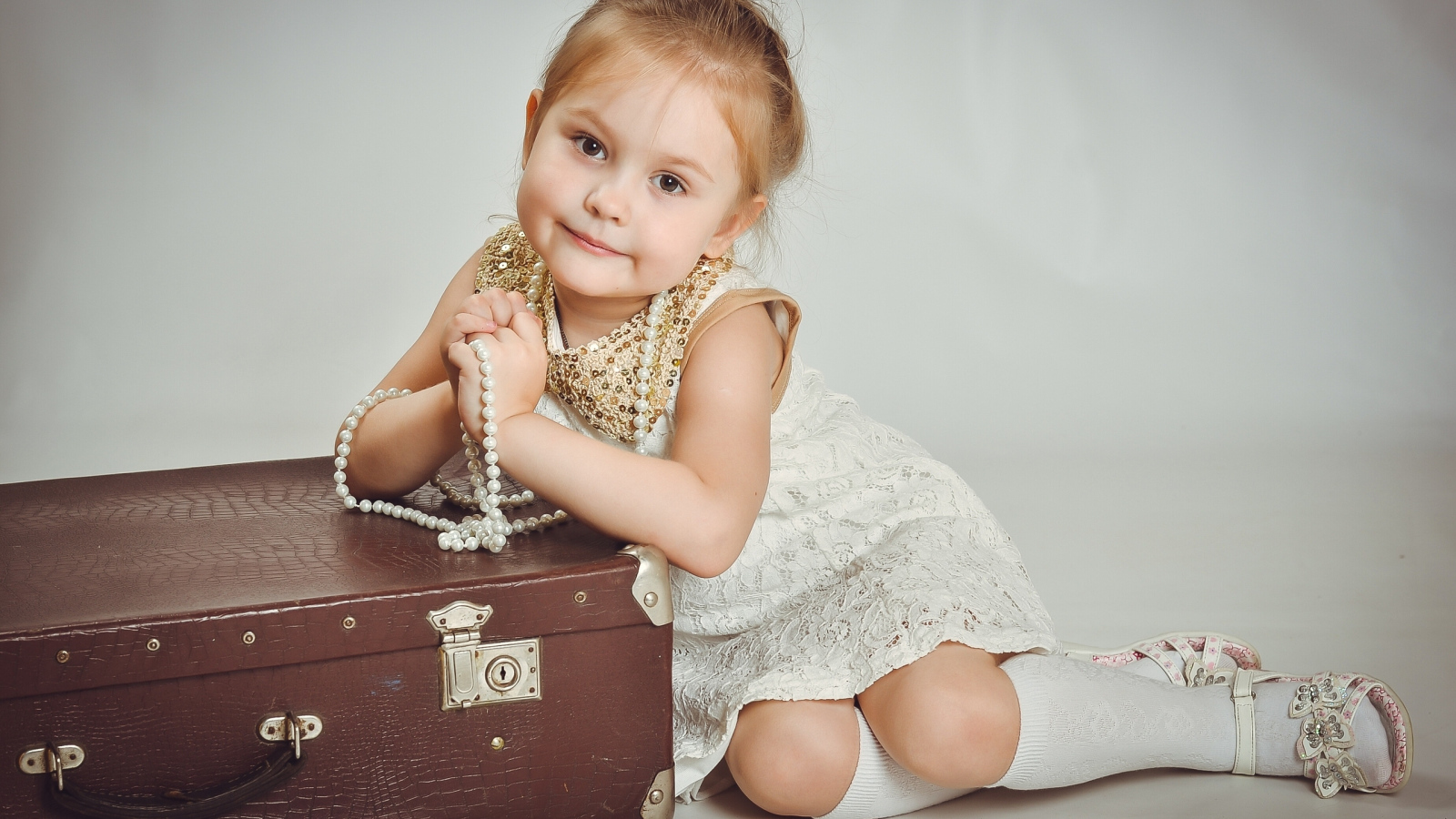 Маленькая девочка в белом платье с чемоданом