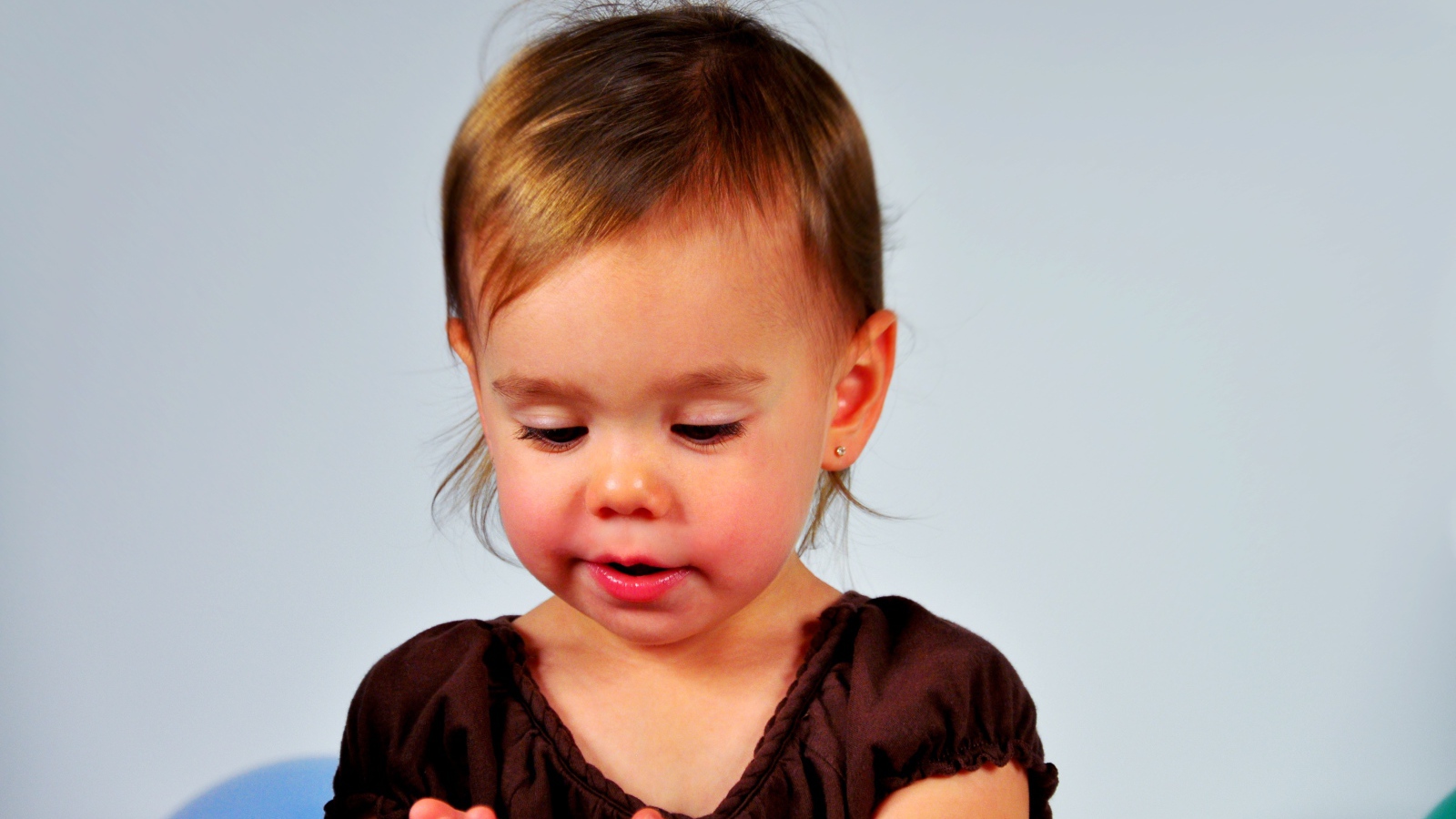 Маленькая девочка смотрит на руки на сером 