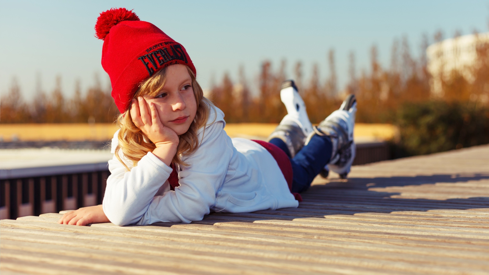 Маленькая девочка на роликах лежит на мосту