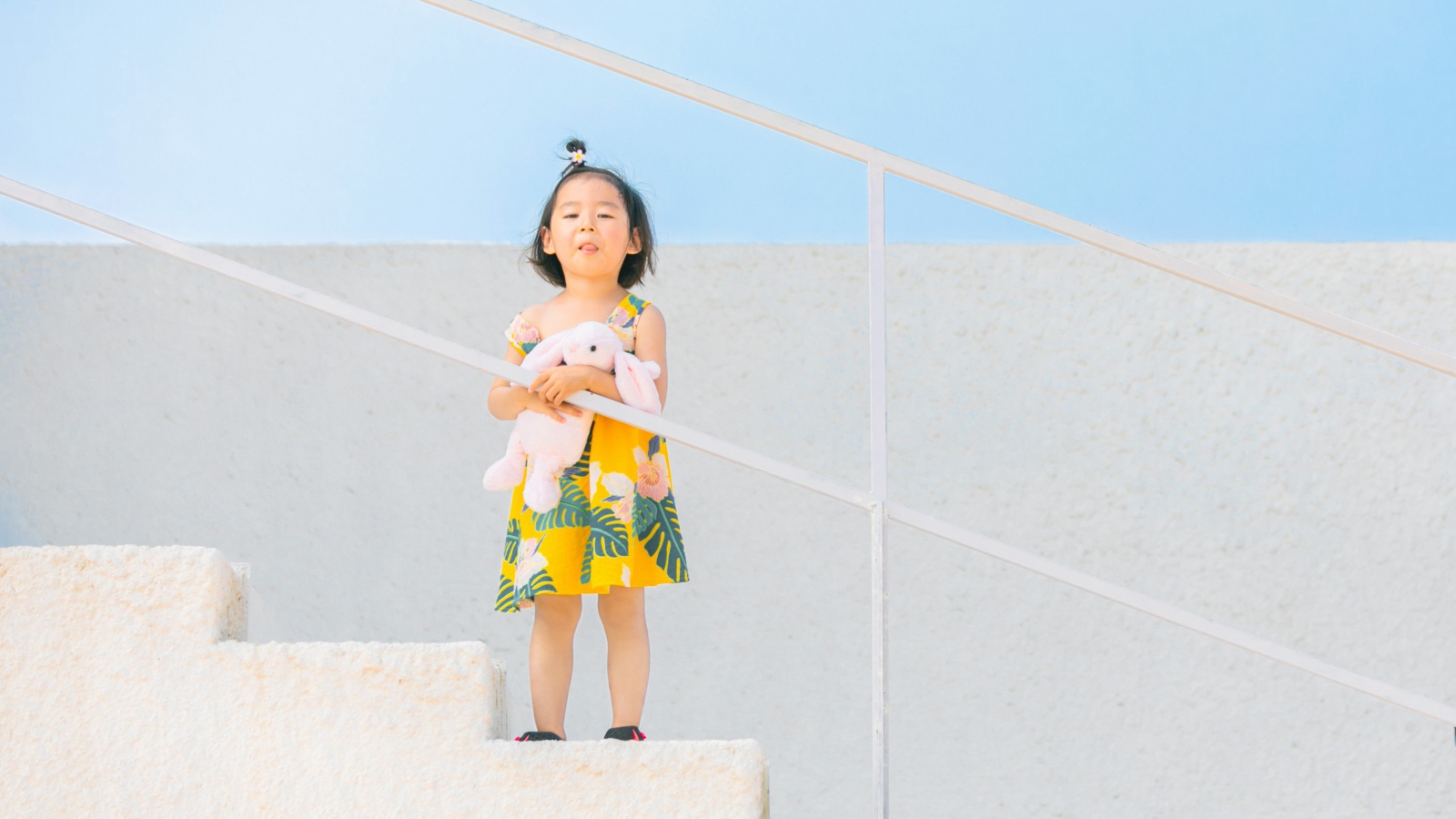 Маленькая девочка с игрушкой на ступеньках 