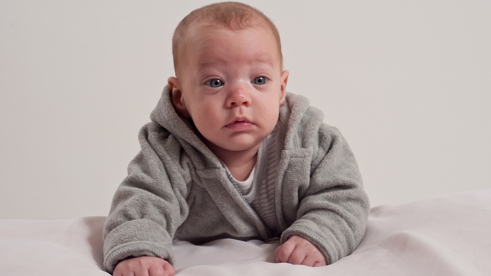 Маленький новорожденный мальчик в сером костюме