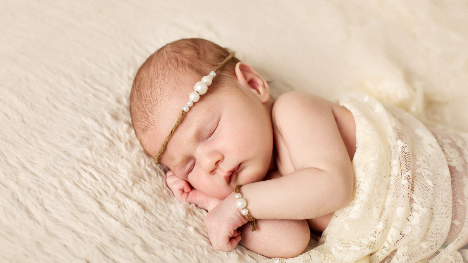 Спящий грудной ребенок с украшением с жемчугом на голове 
