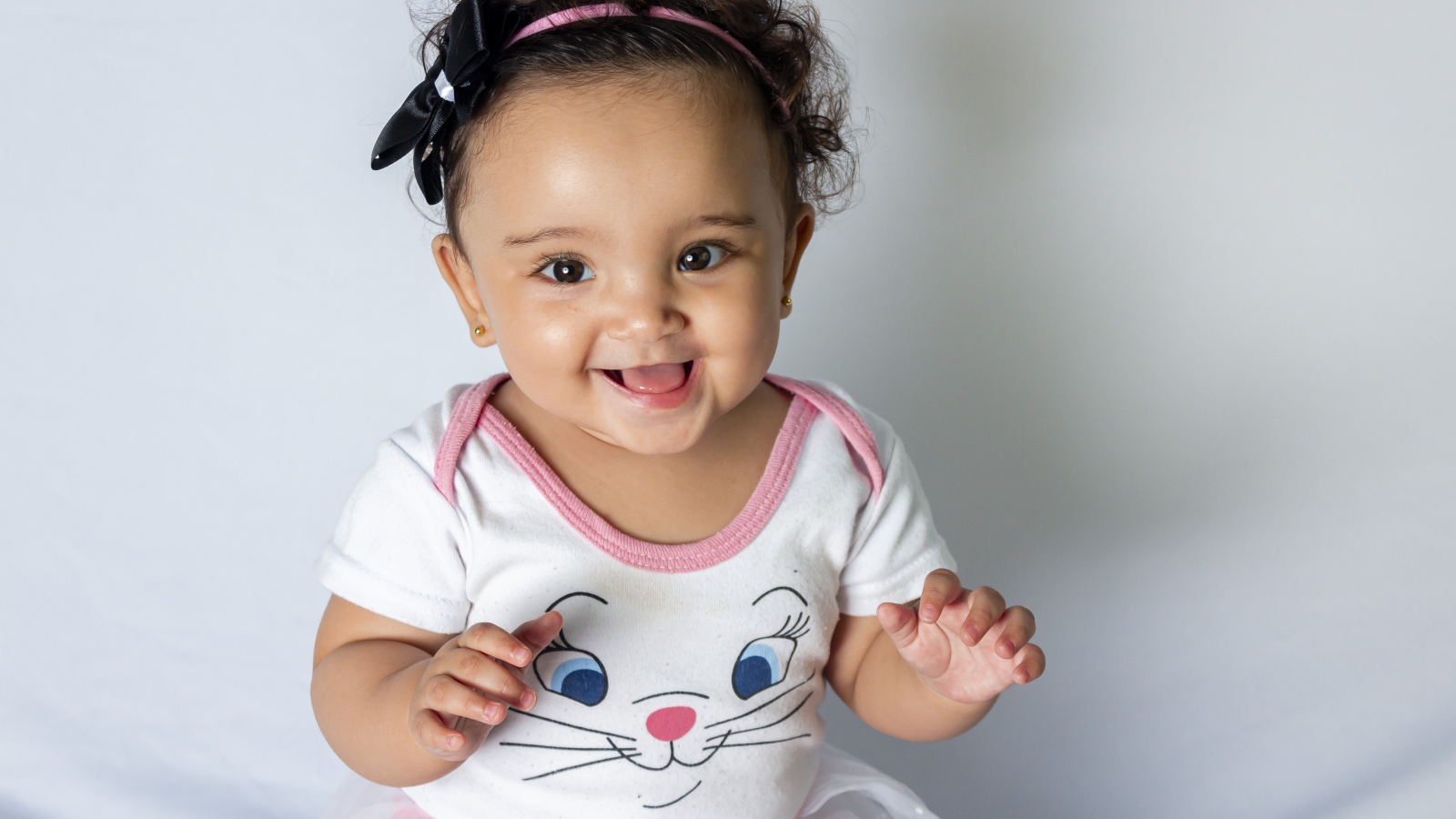 Улыбающаяся маленькая девочка на сером фоне 