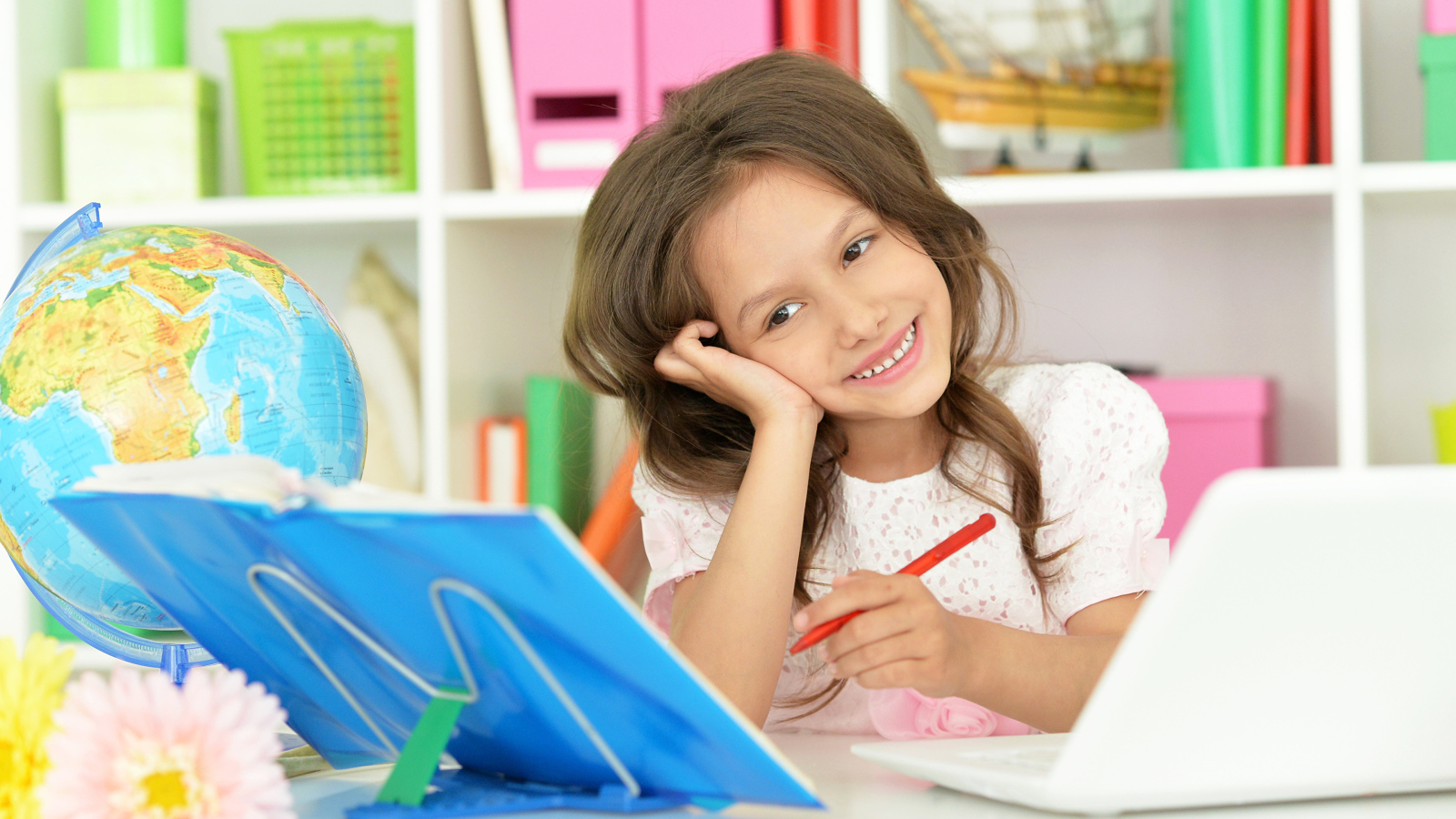 Улыбающаяся девочка ученица делает уроки 