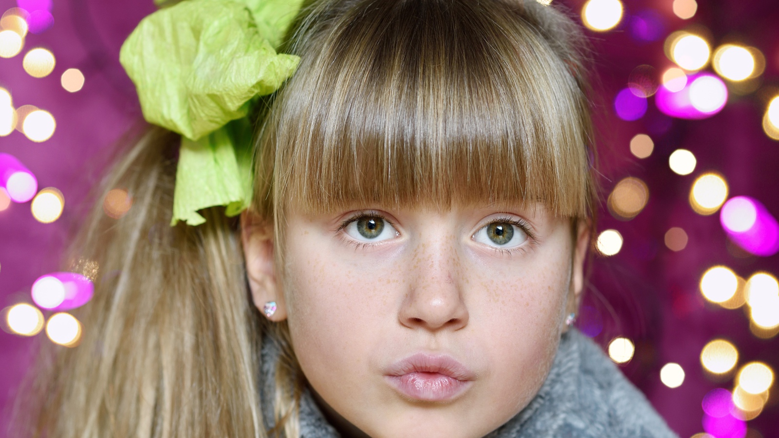 Лицо зеленоглазой девушки с бантом на голове 