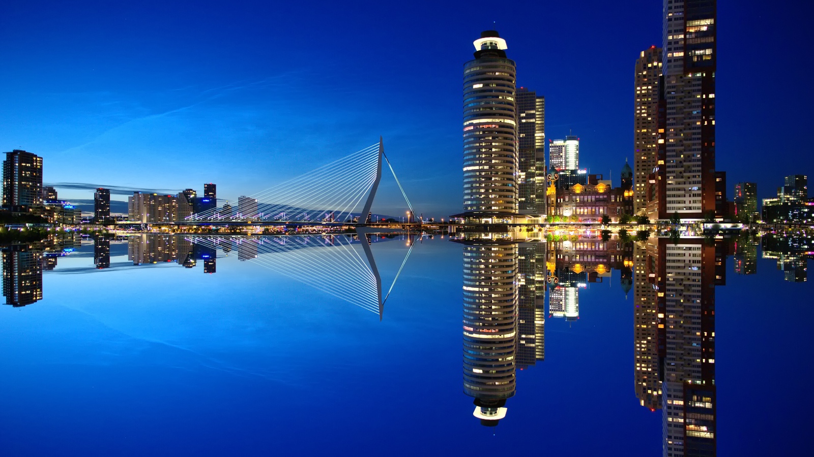 Небоскребы и мост отражаются в тихой воде