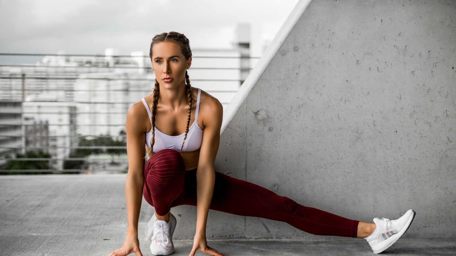 Спортивная девушка делает растяжку у стены 