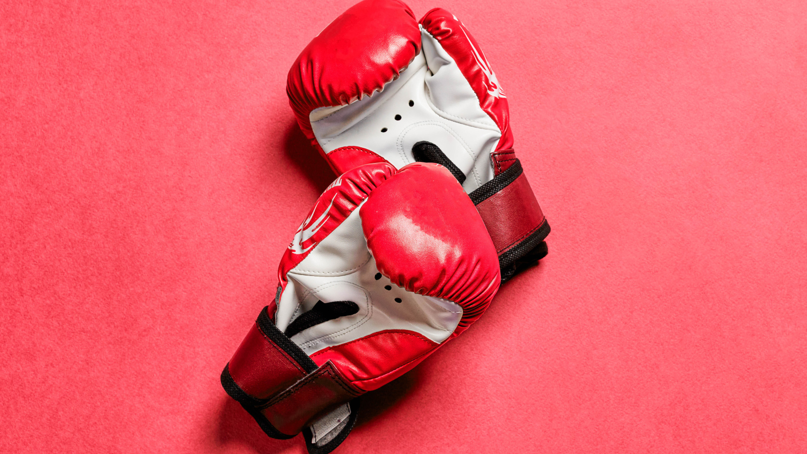Красные боксерские перчатки на розовом фоне 