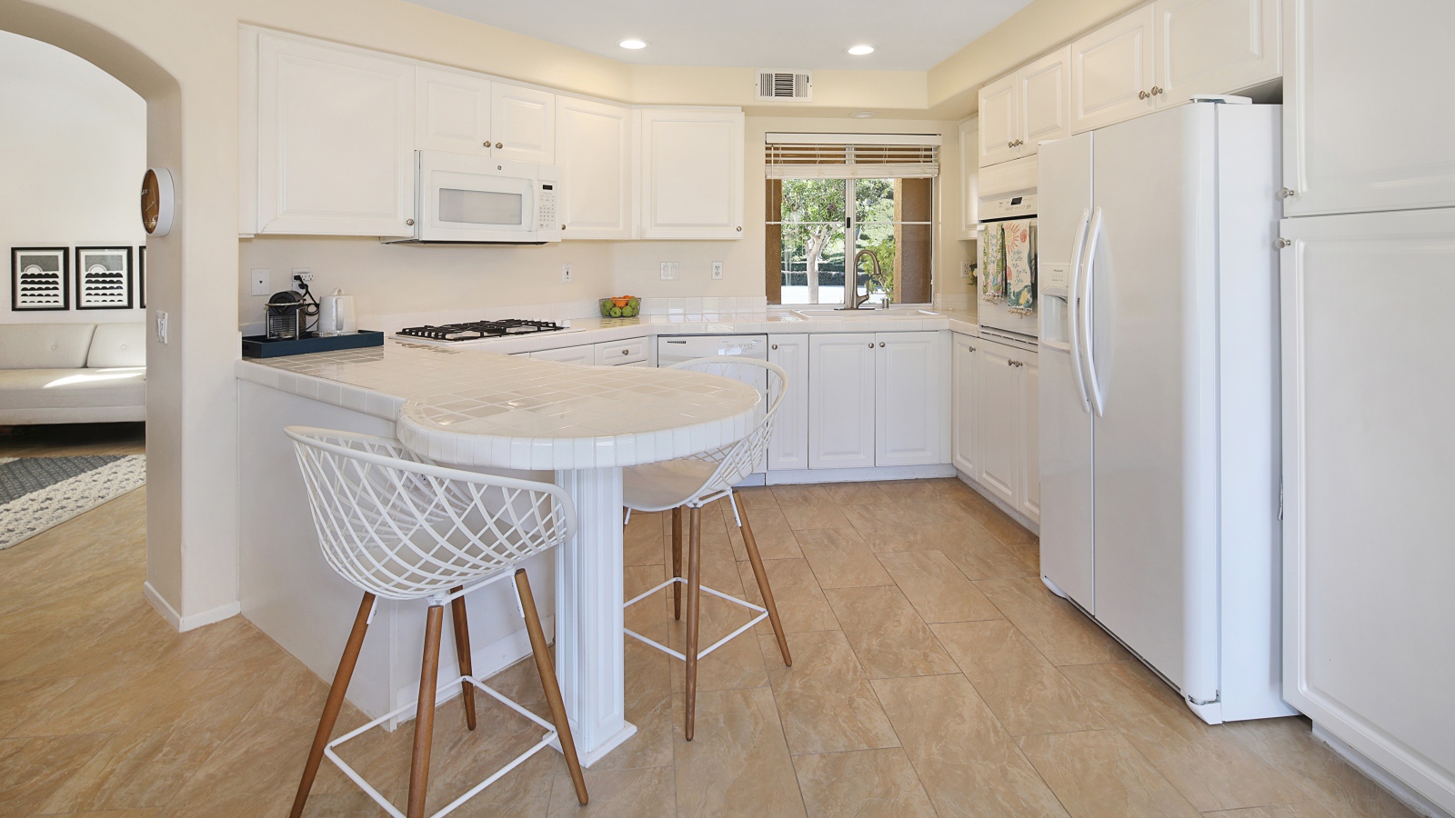 Белая стильная мебель с большим холодильником на кухне