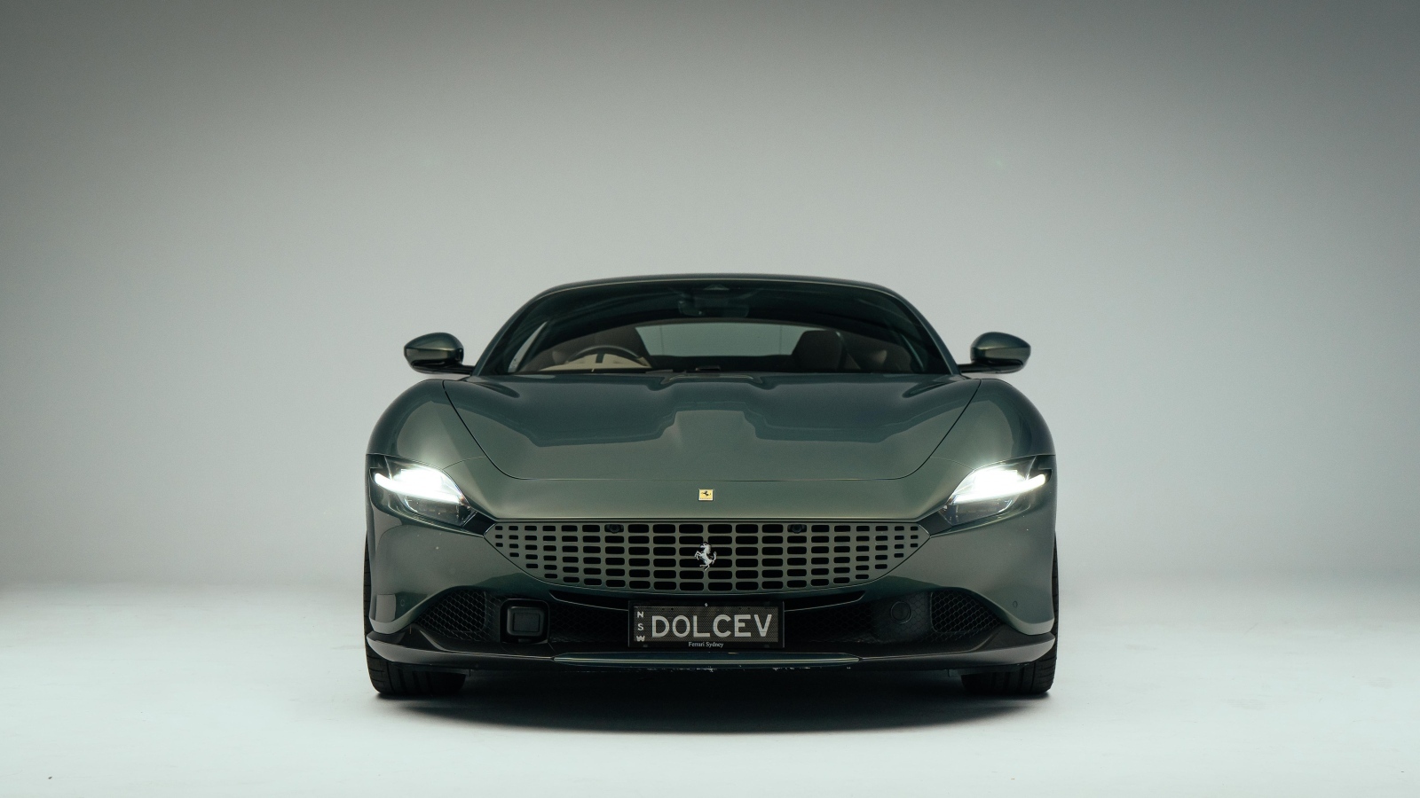 Автомобиль Ferrari Roma на сером фоне вид спереди