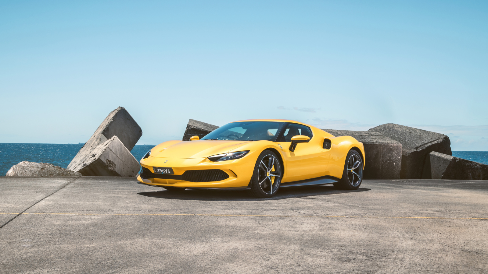 Желтый автомобиль Ferrari 296 GTB у камней