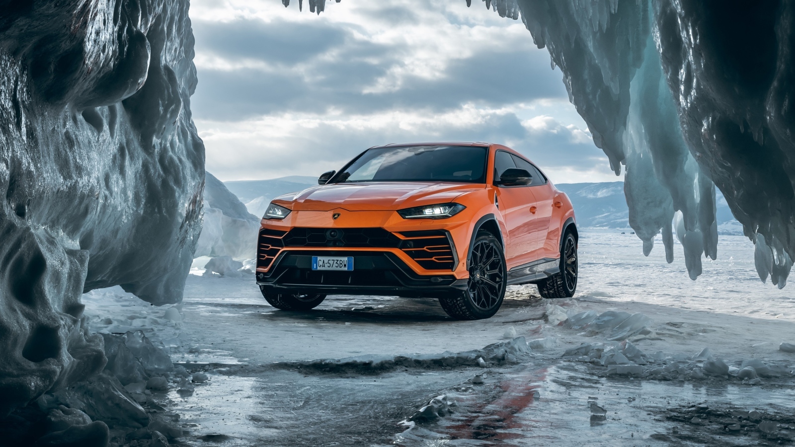 Оранжевый внедорожник Lamborghini Urus у ледяной пещеры