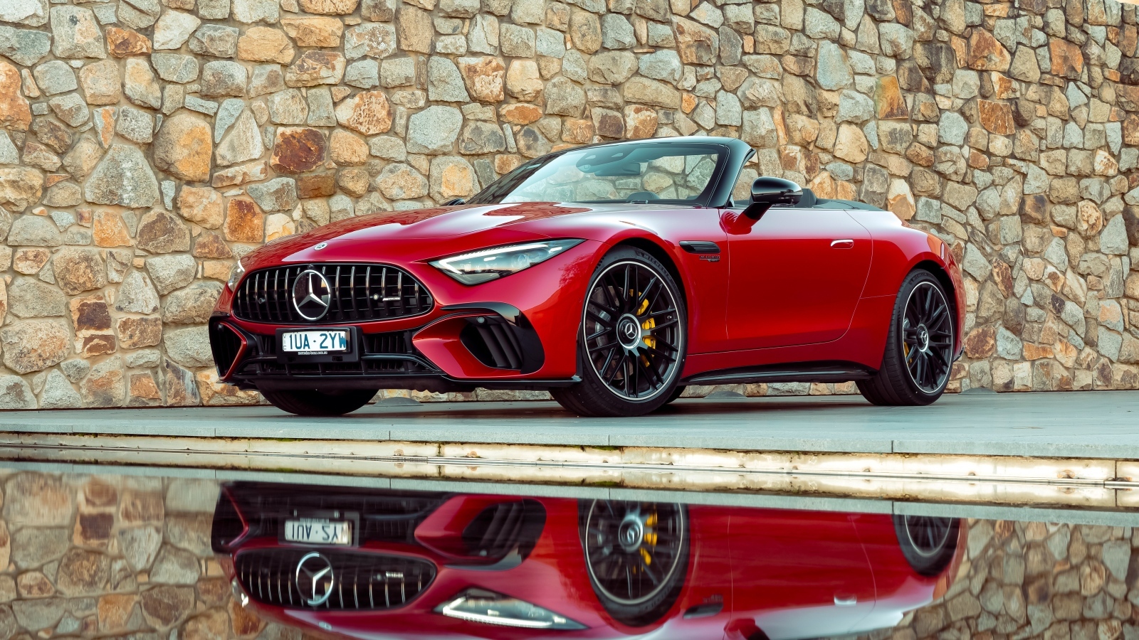 Красный Mercedes-AMG SL 63 4MATIC+ 2023 года на фоне стены