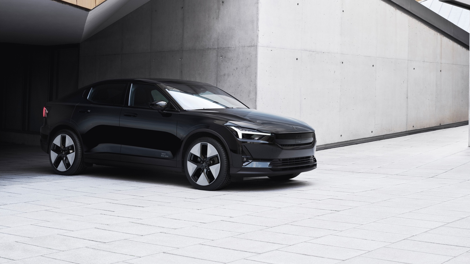 Черный автомобиль Polestar 2 2023 года у серой стены
