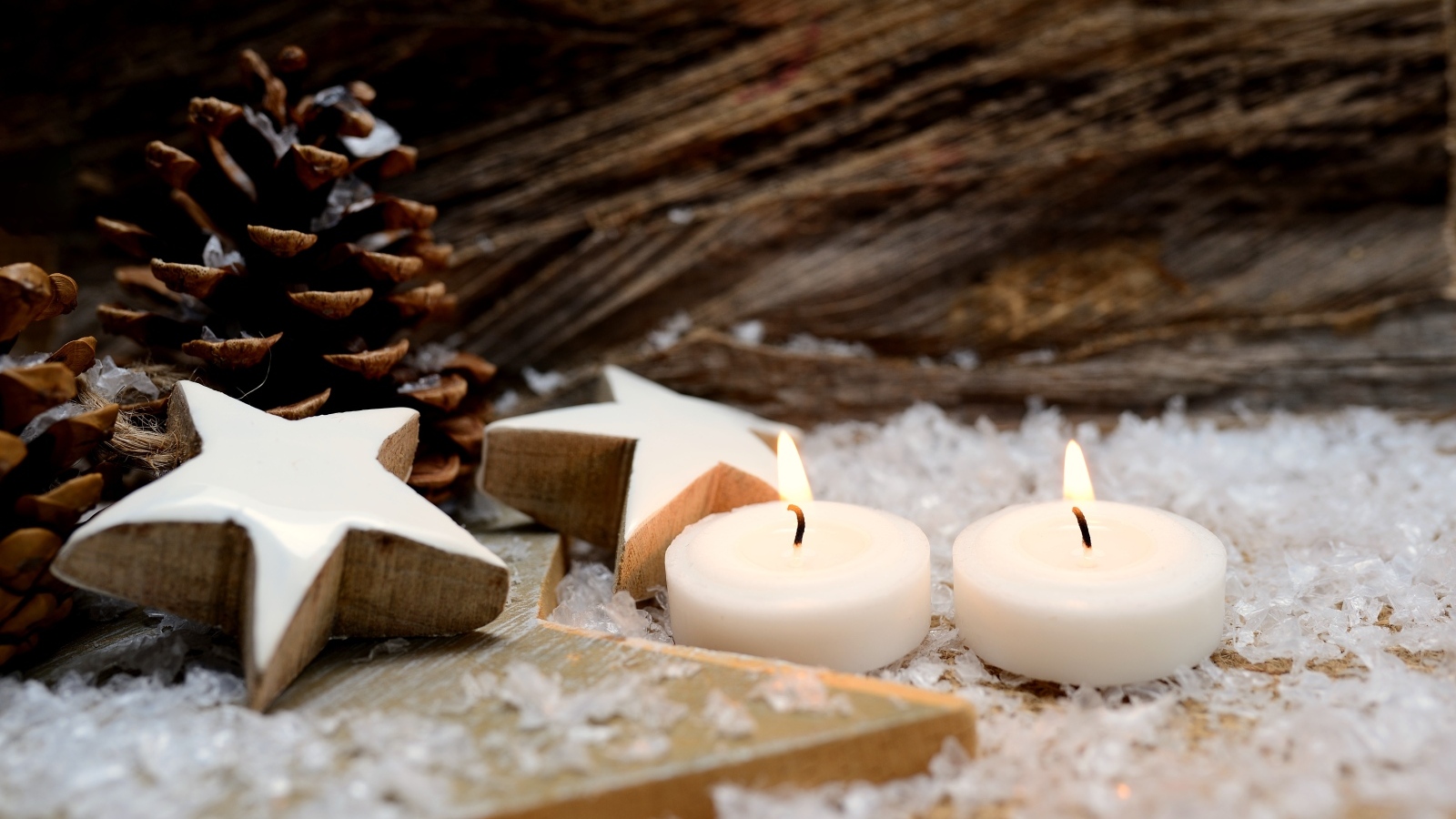 Две зажженные свечи, шишки и звезды