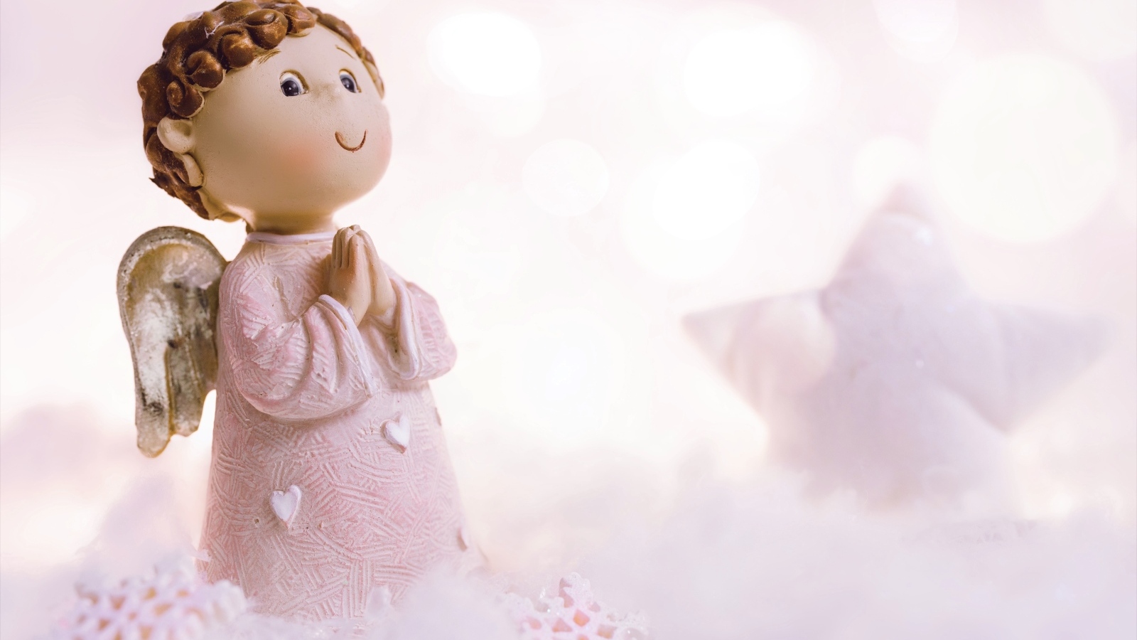 Маленькая статуэтка ангела стоит на снегу