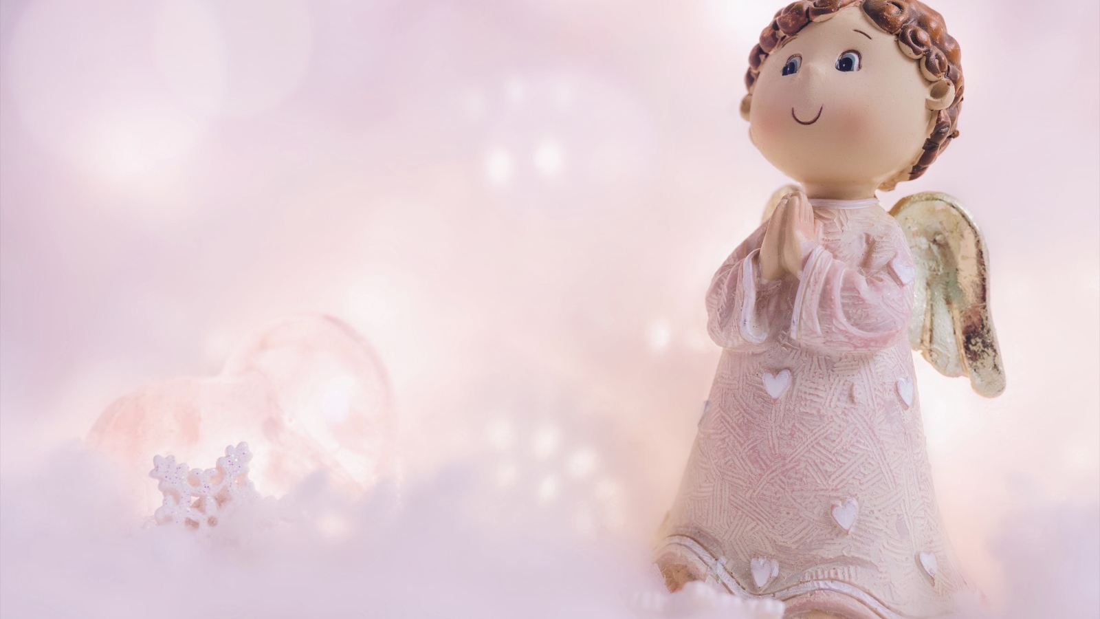 Статуэтка ангела на розовом фоне