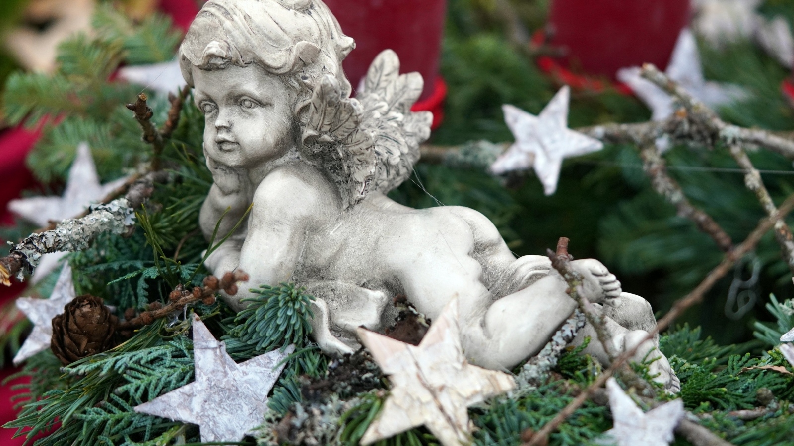 Статуэтка ангел лежит на ветках туи