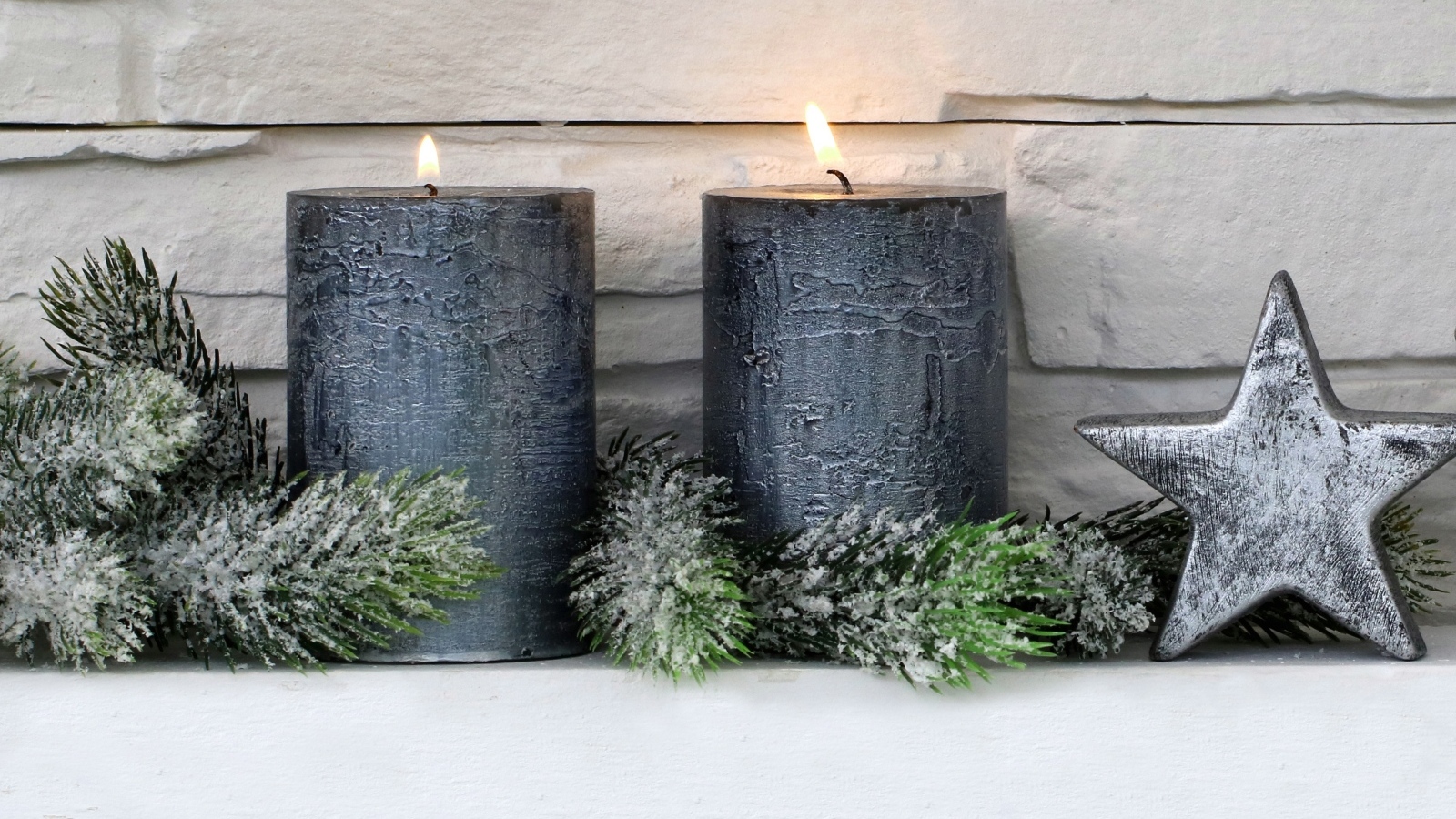 Две большие зажженные свечи у стены