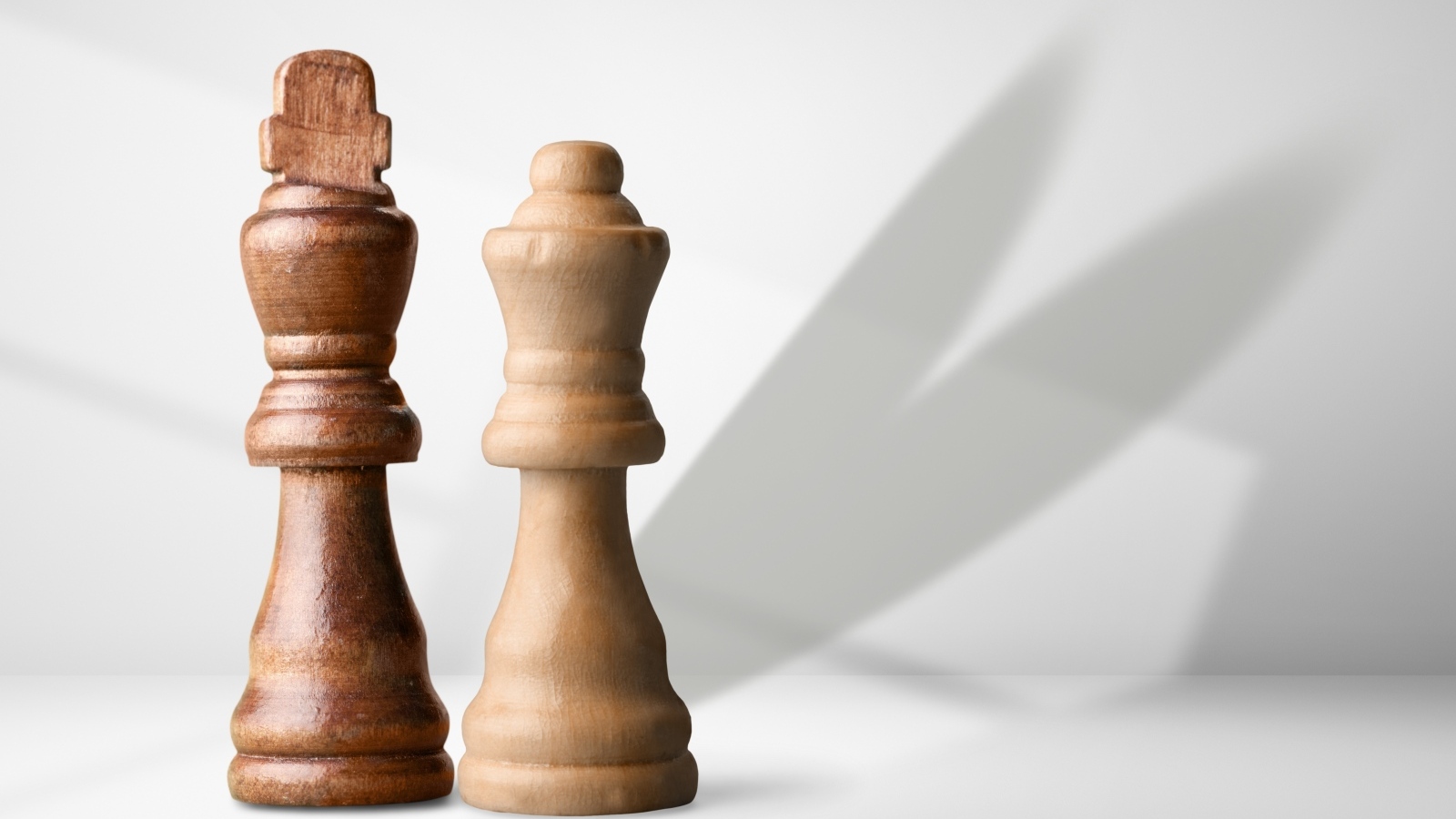 Две деревянные шахматные фигуры на сером фоне