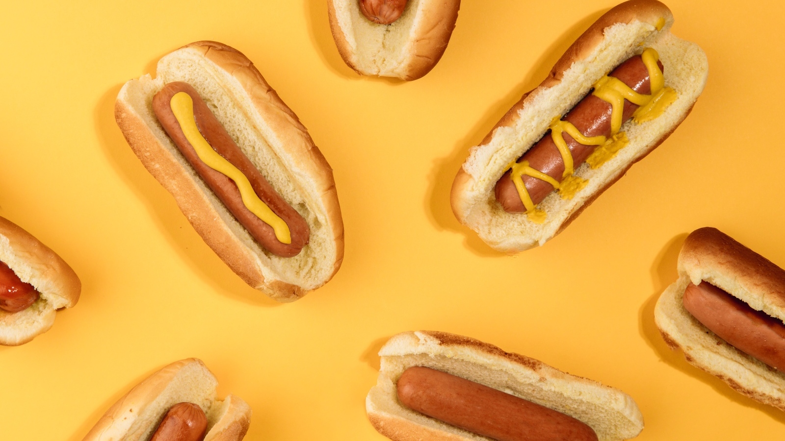Аппетитные хот доги на желтом столе