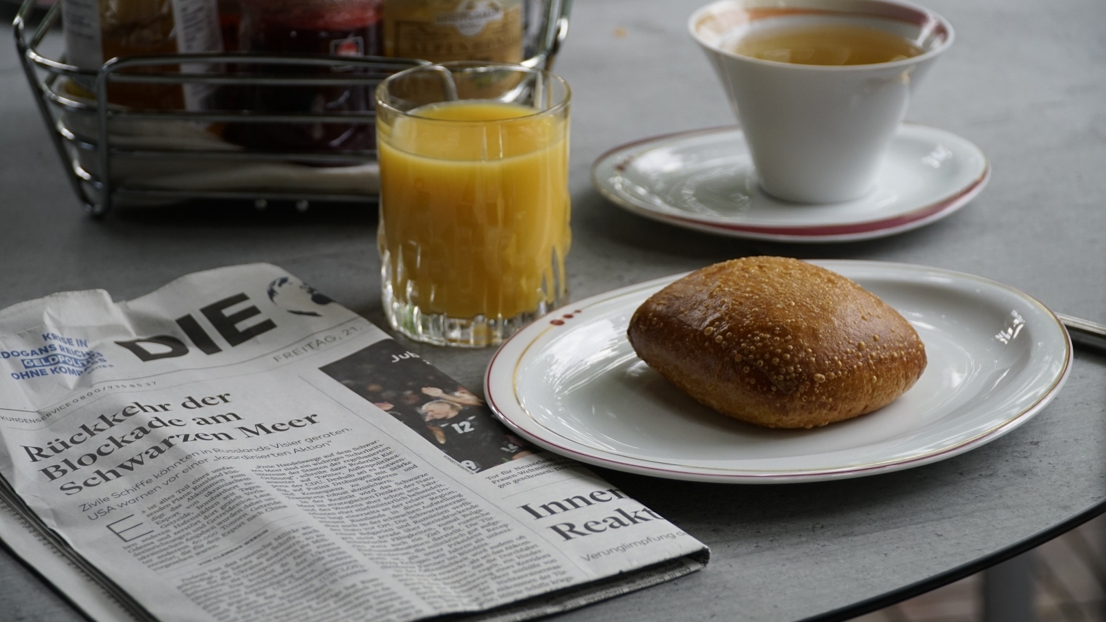 Булочка и стакан сока на столе с газетой