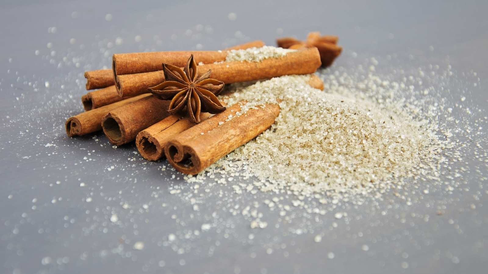 Корица, коричневый сахар и бадьян на сером фоне