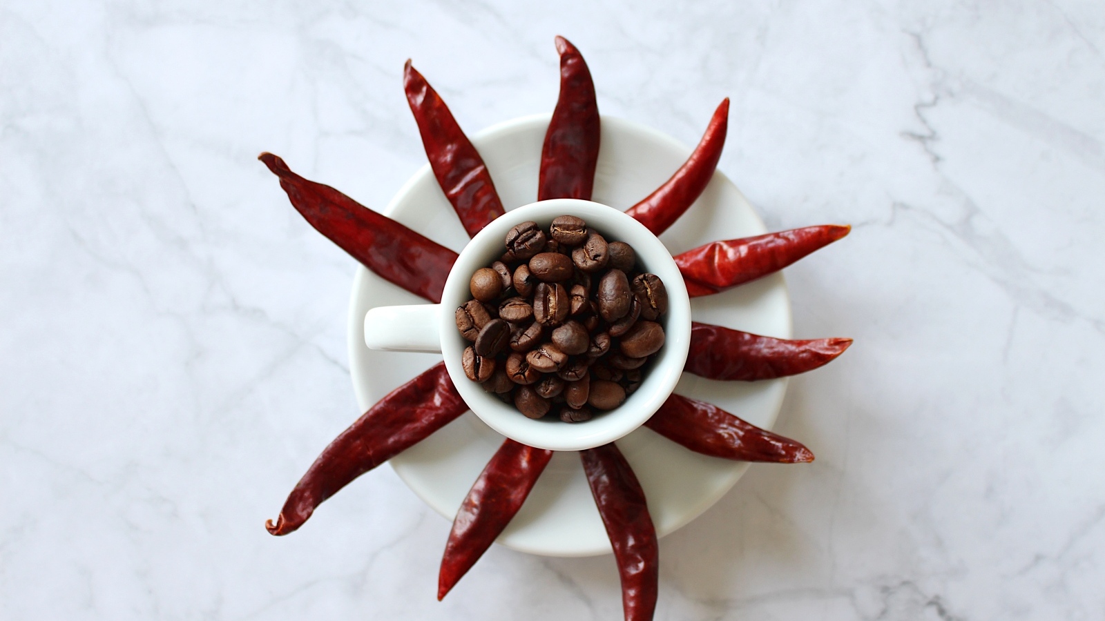 Кофейные зерна в чашке на тарелке с красным перцем