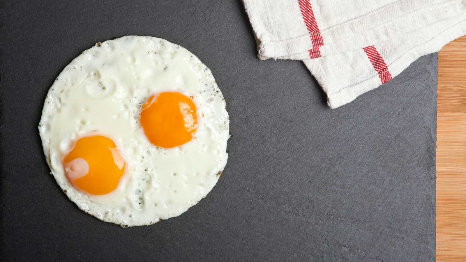 Яичница глазунья на сером столе с полотенцем