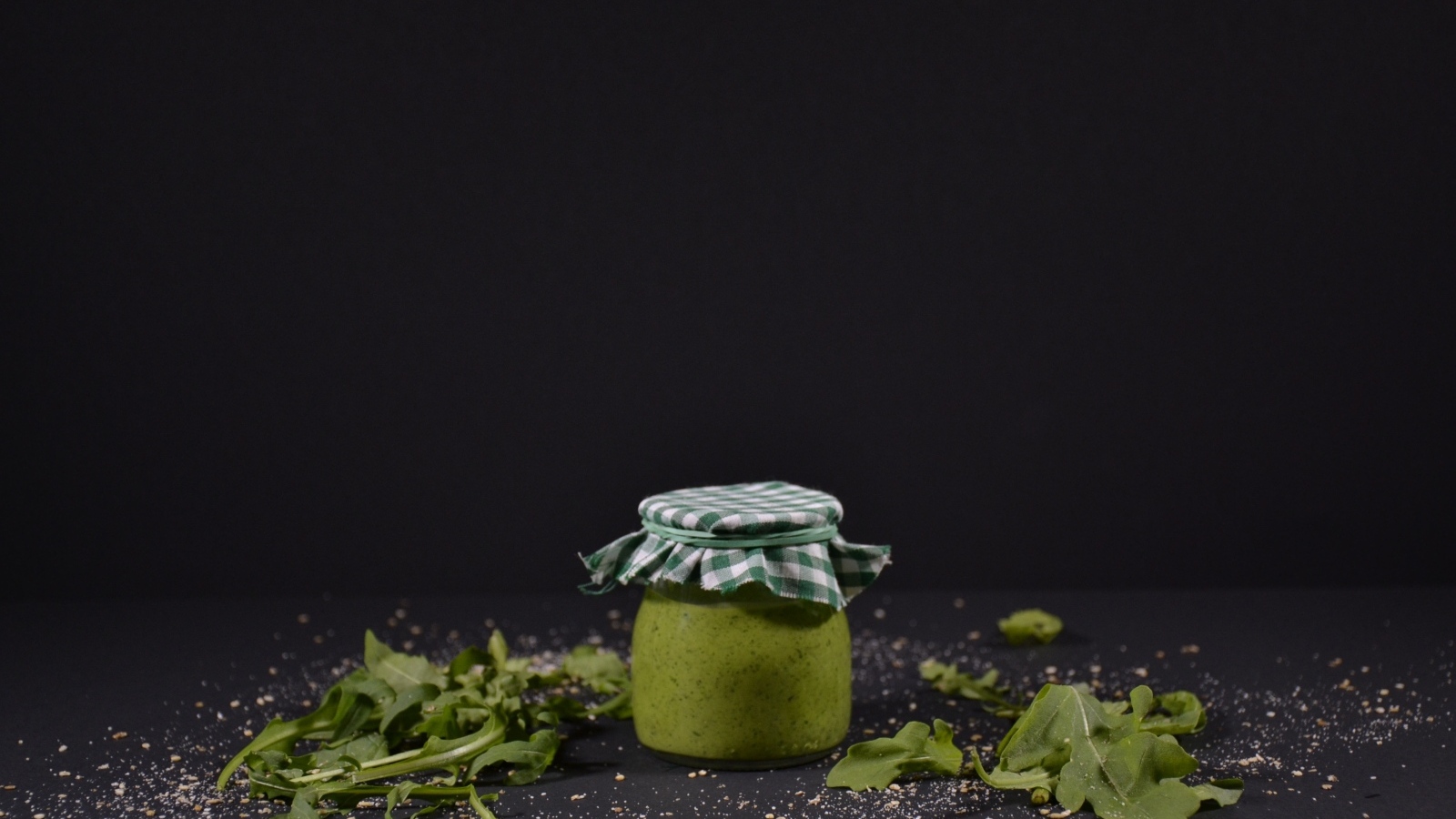 Банка соуса песто на черном фоне
