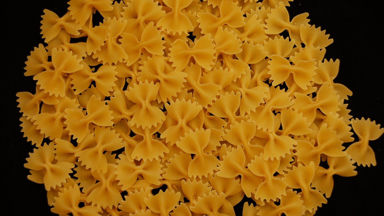 Макароны в форме бантиков на черном фоне