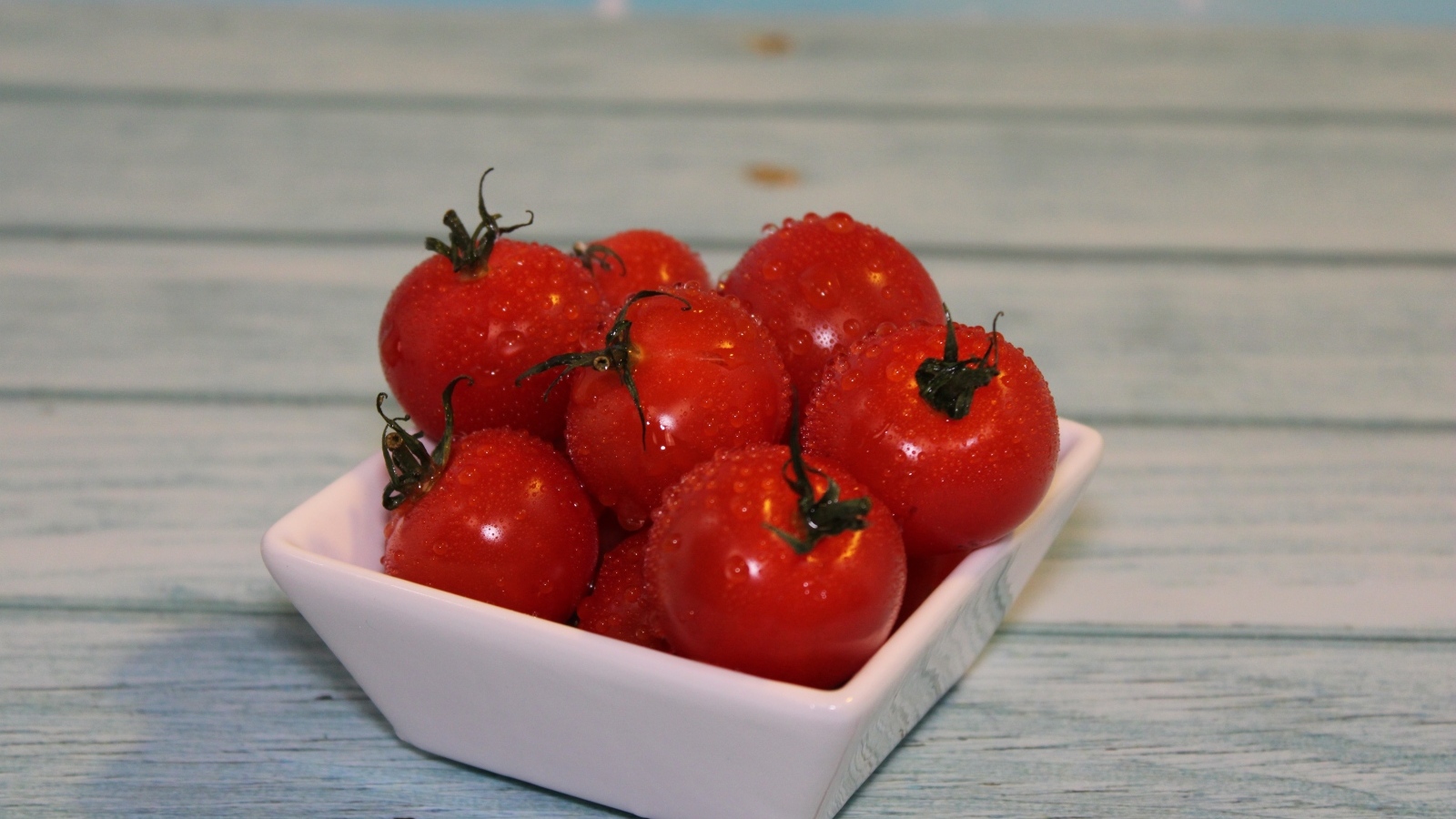 Красные мокрые помидоры в белой тарелке