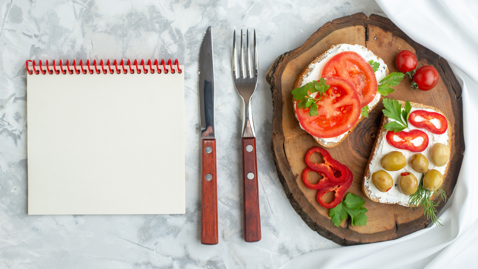 Бутерброды на столе со столовыми приборами и блокнотом