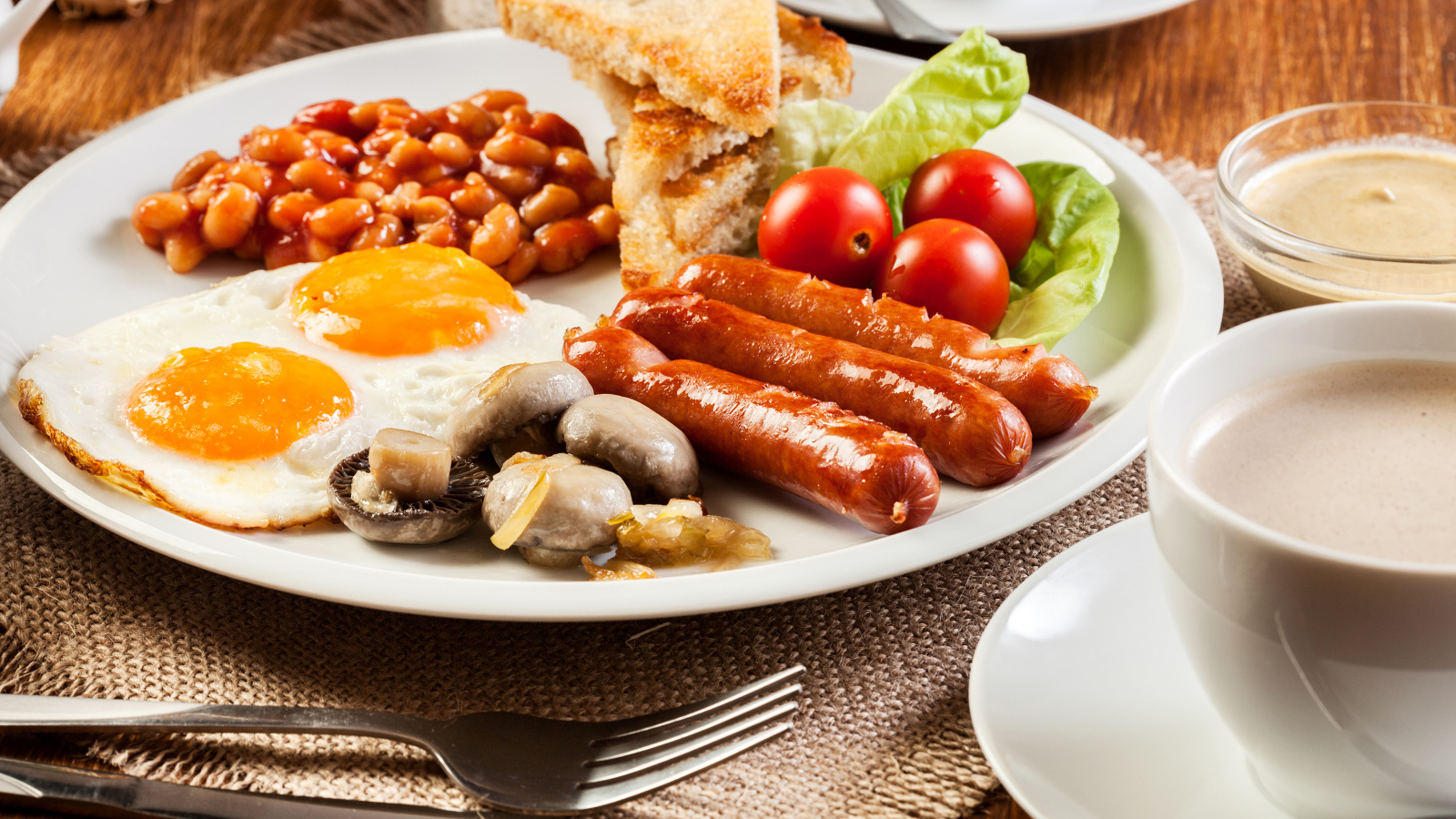 Яичница, сосиски и овощи на тарелке на завтрак