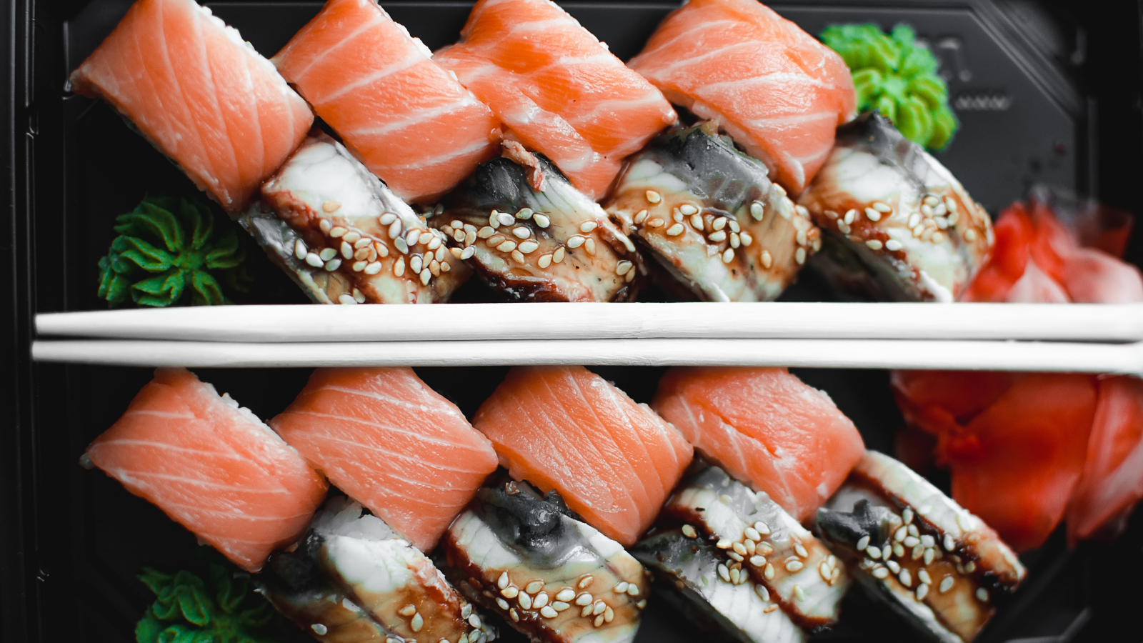 Суши с рыбой на черной тарелке с палочками