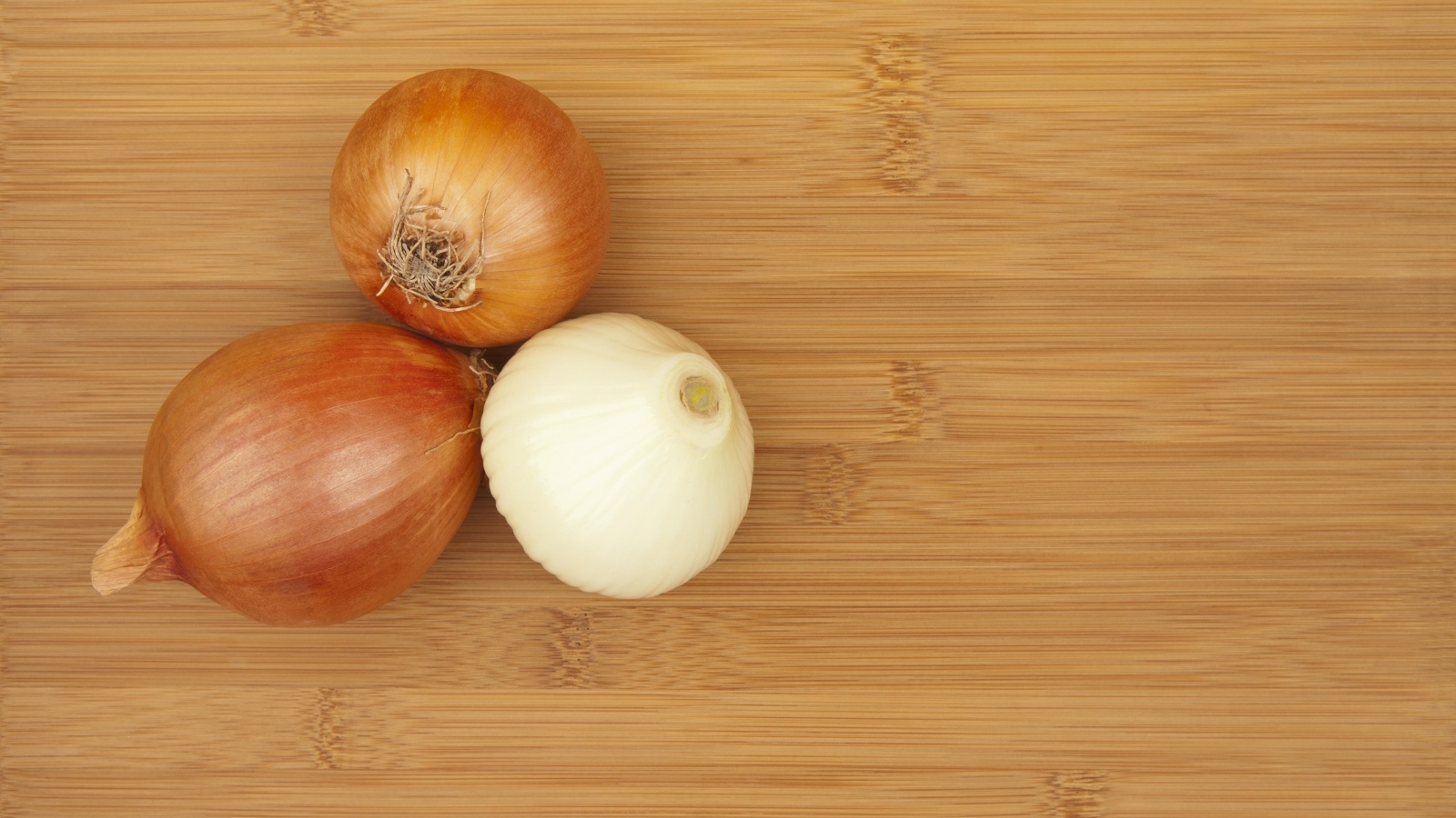 Три луковицы на деревянном столе