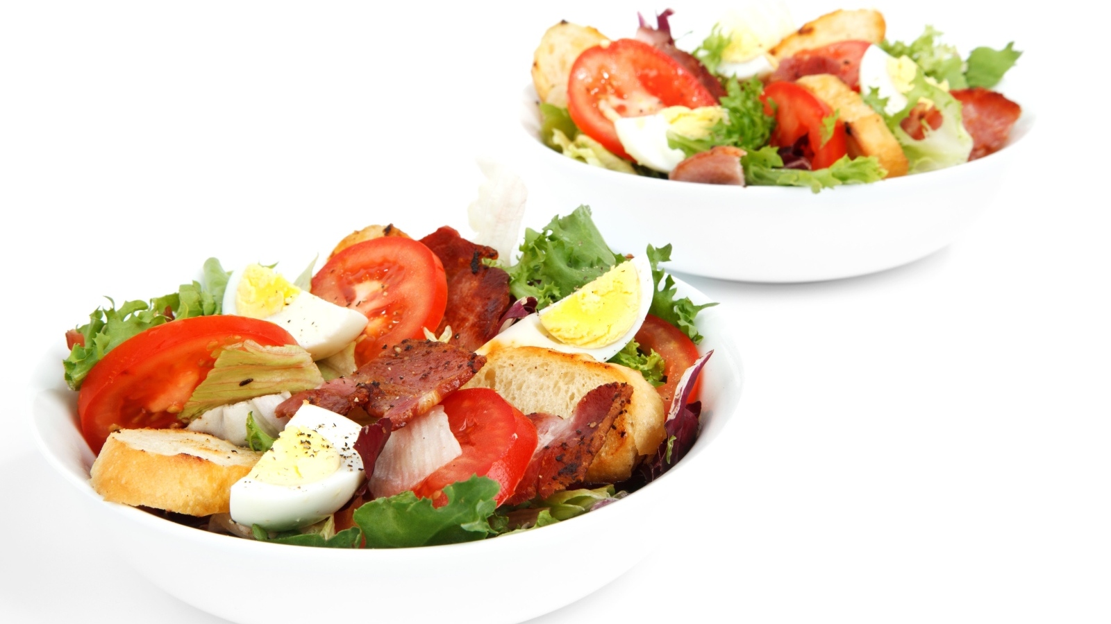 Две миски вкусного салата на белом фоне