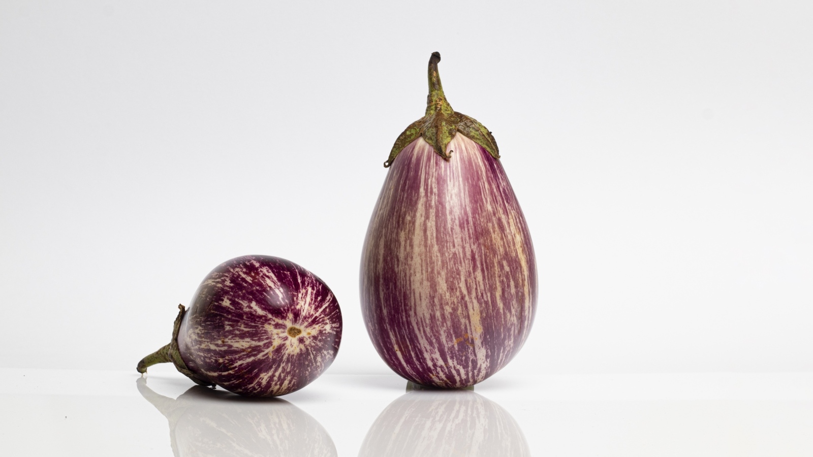 Два баклажана на сером фоне