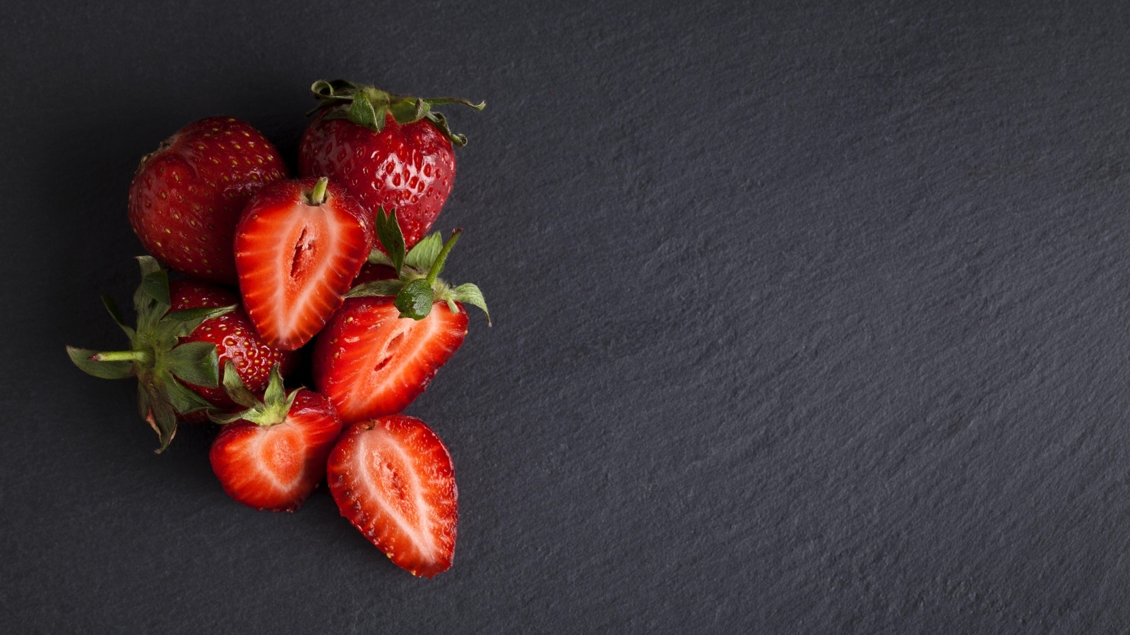 Горсть спелой клубники на сером столе